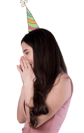 A delighted girl in a party hat covering her mouth in surprise