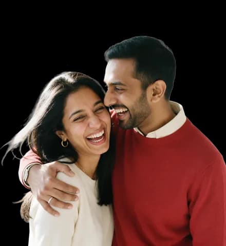 A young couple laughing together, his arm around her shoulder